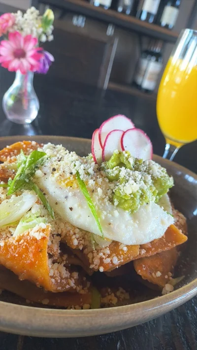Chilaquiles with fried egg, cotija cheese, avocado, and radish.