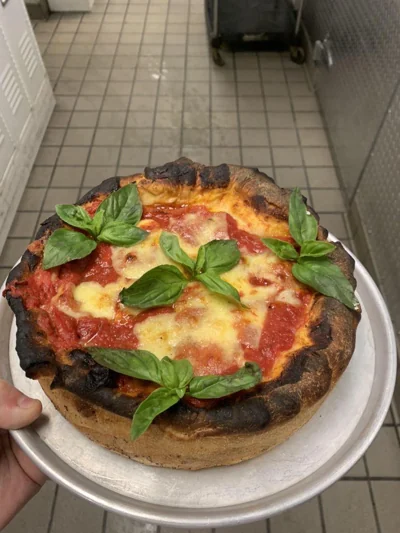 Deep-dish margherita pizza with fresh basil.